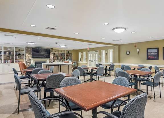 A room with tables and chairs and a television.