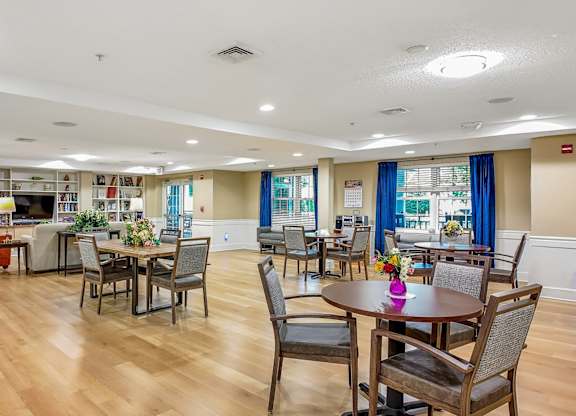 A large room with tables and chairs and a bookshelf.