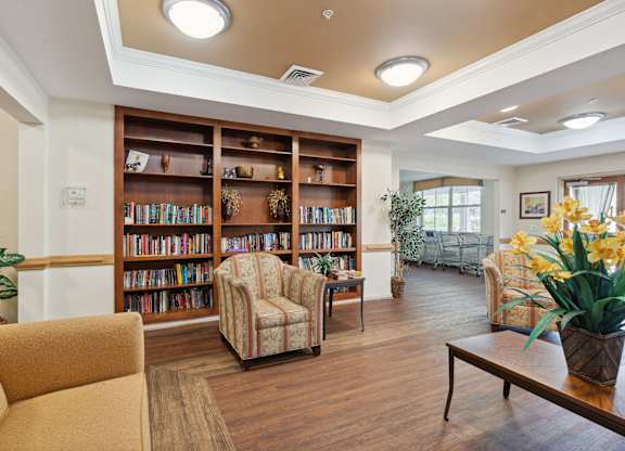 a seating area with couches and chairs and a bookshelf with books