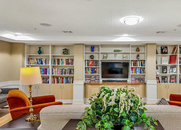A living room with a large bookshelf filled with books and a flat screen TV mounted on the wall.