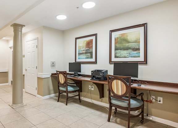 A hallway with a desk and chairs on the right side.