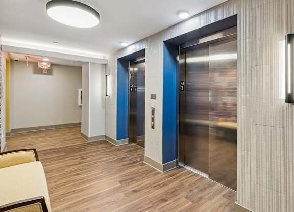 A hallway with two elevators, one blue and one silver.