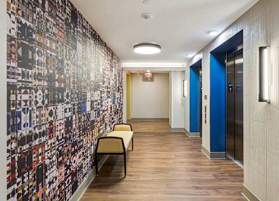 A hallway with a wall covered in pictures and a bench.
