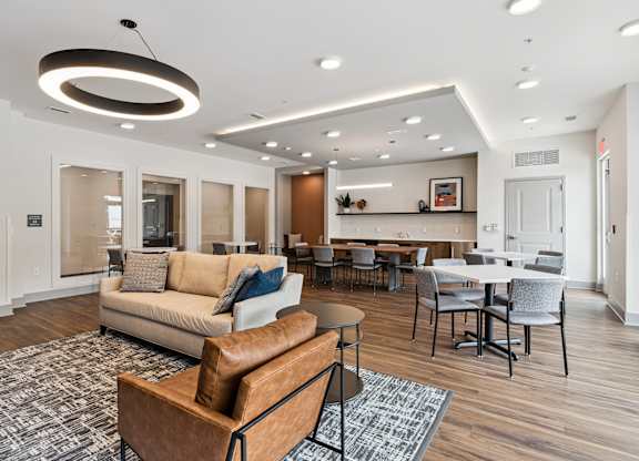 A modern living room with a brown leather sofa and a grey rug.