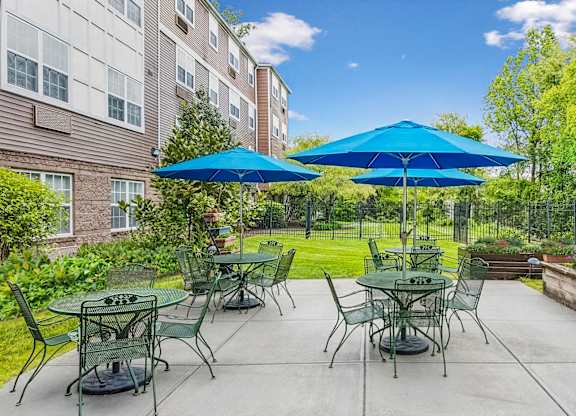 A patio with tables and chairs and umbrellas.