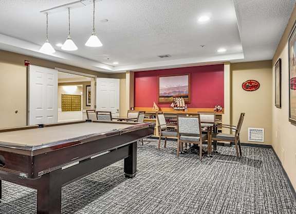 A room with a pool table and a dining table.
