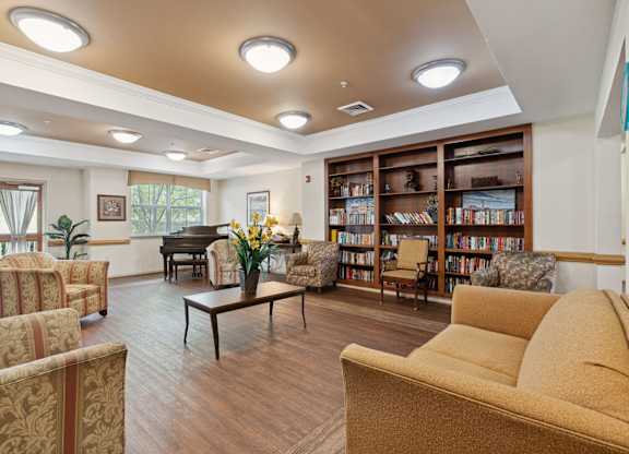a room with couches chairs and a table with a vase of flowers and a piano