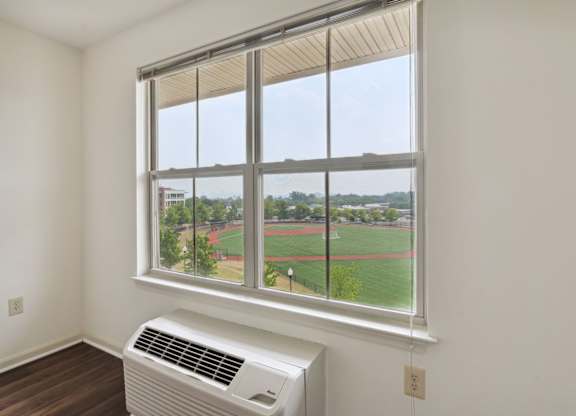 A room with a window overlooking a baseball field.
