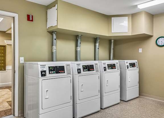 A row of washing machines are lined up in a laundry room.