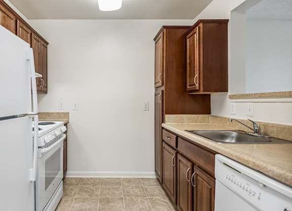 A kitchen with white appliances and brown cabinets.