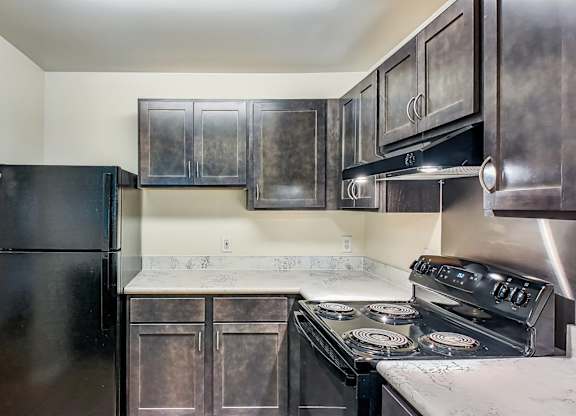 A black fridge and stove in a kitchen with a white door.