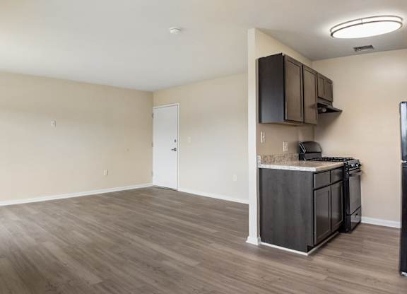 A kitchen area with a refrigerator, microwave, and cabinets.
