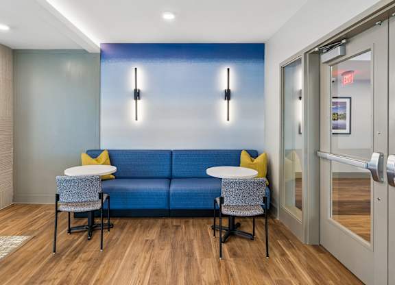 A blue couch with two yellow pillows and two chairs with a glass door in the background.