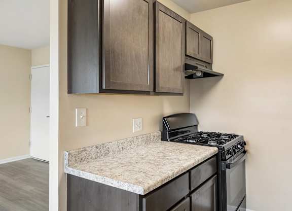 A kitchen with a black stove top oven and a counter top with a granite counter top.