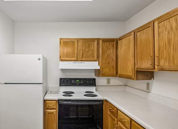 A kitchen with a white refrigerator and wooden cabinets.