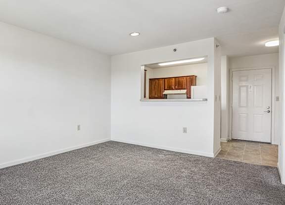 A spacious room with a carpeted floor and a door on the right side.