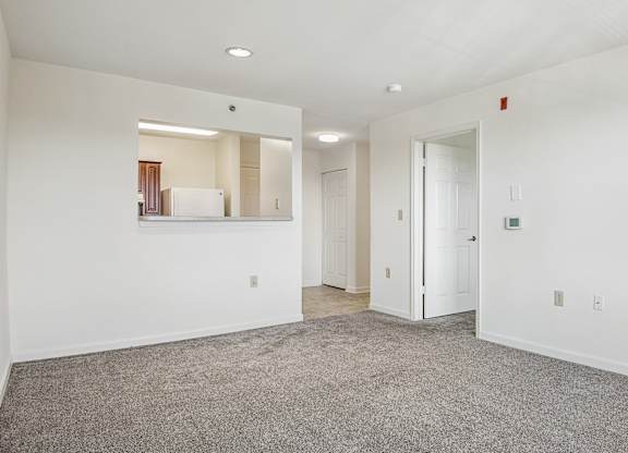 A spacious room with a carpeted floor and white walls.