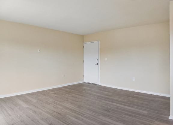 Empty room with wooden flooring and white walls.