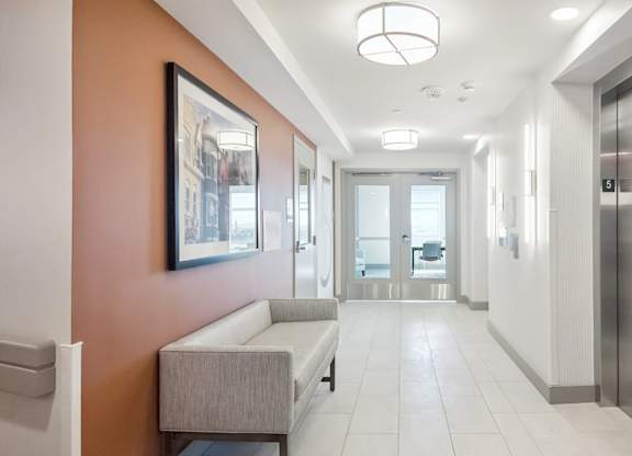 A hallway with a bench and a framed picture on the wall.