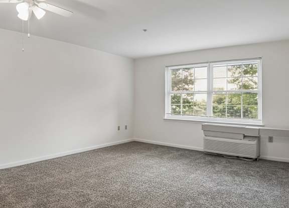 A room with a ceiling fan and a window with blinds.