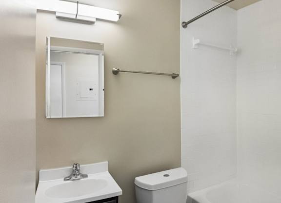 A white bathroom with a sink, toilet, and shower.