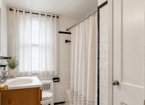A white bathroom with a black and white tiled floor.