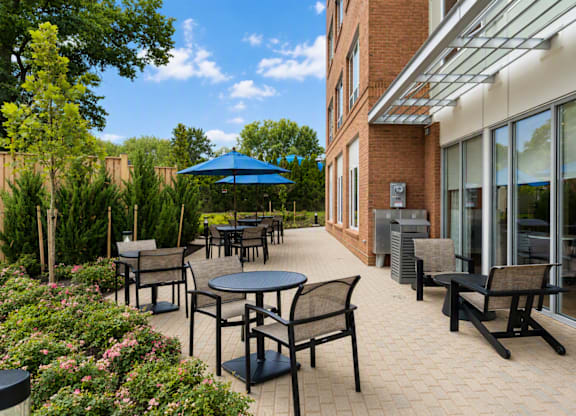 A patio with tables and chairs and a blue umbrella.
