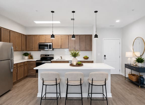 A modern kitchen with a white island and bar stools.
