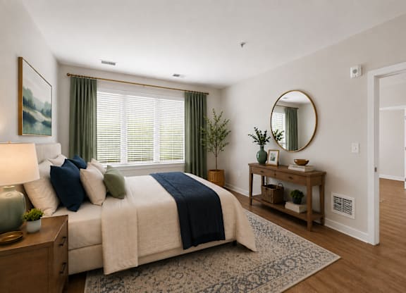 A bedroom with a bed, nightstand, and a round mirror on the wall.