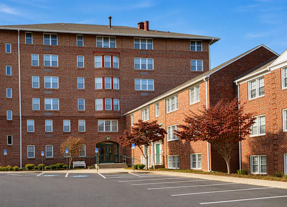 A large red brick building with a parking lot in front.