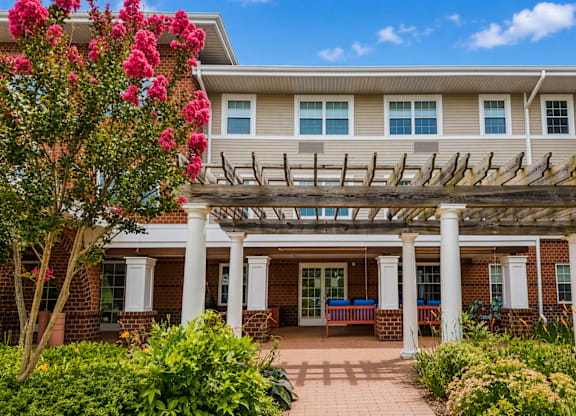 A house with a covered patio and a tree with pink flowers.
