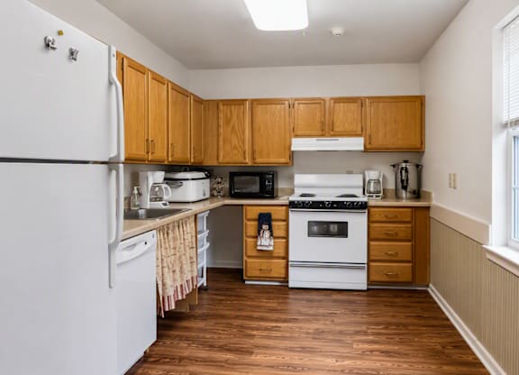 A kitchen with white appliances and wooden cabinets.