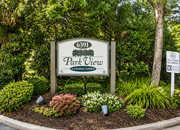 A sign for Park View is surrounded by flowers and trees.