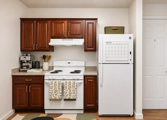 A white stove and refrigerator in a kitchen with brown cabinets.