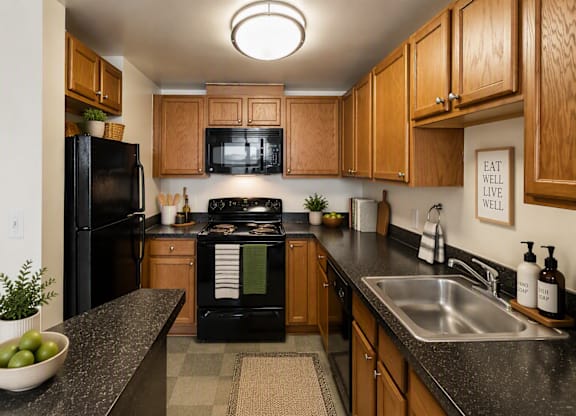 A kitchen with black appliances and wooden cabinets.