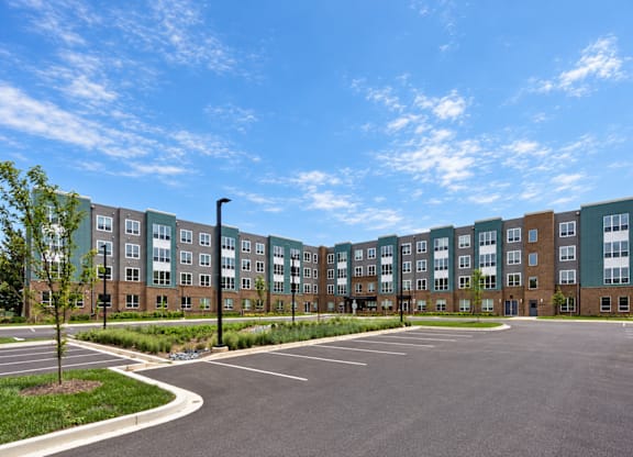 A large parking lot in front of a multi-story apartment building.