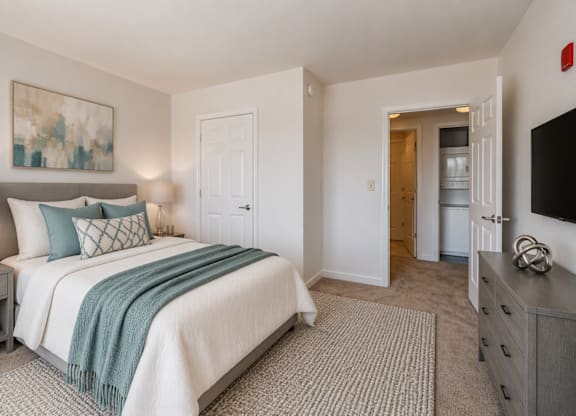 A bedroom with a bed, nightstand, and a painting on the wall.