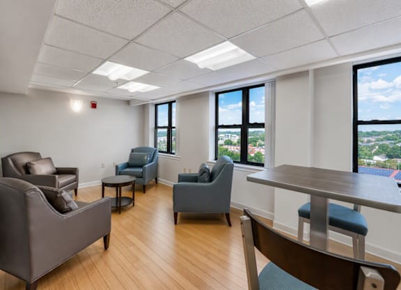 A room with a table, chairs and a view of the city.