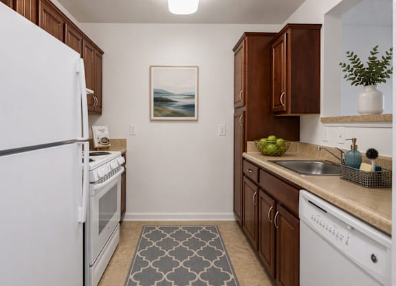 A kitchen with white appliances and brown cabinets.