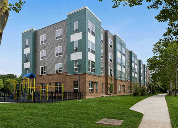 A long building with a playground in front of it.