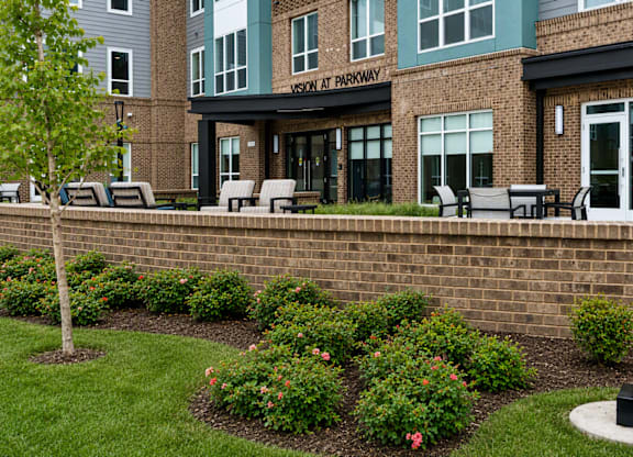 A brick wall with a flower bed in front of a building with a sign that says
