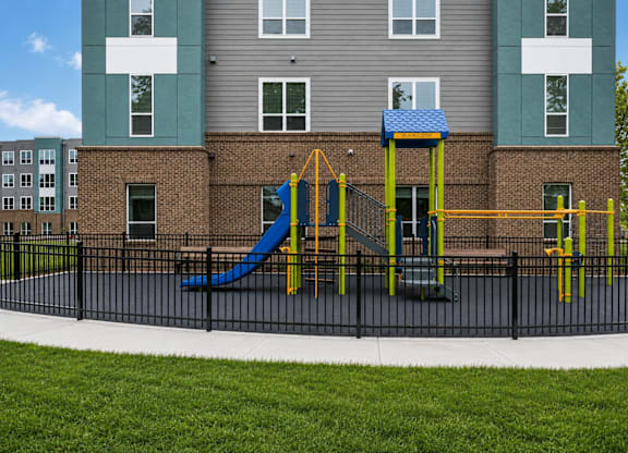 A playground with a blue slide and yellow poles in front of a building.