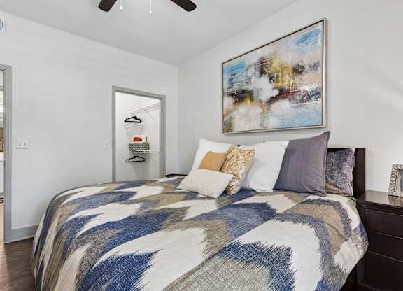A bedroom with a large bed and a painting on the wall.