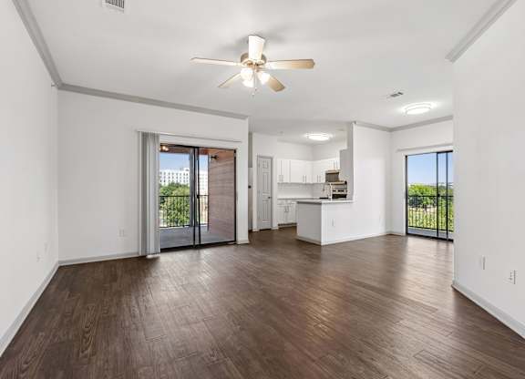 A spacious living room with a ceiling fan and hardwood floors.