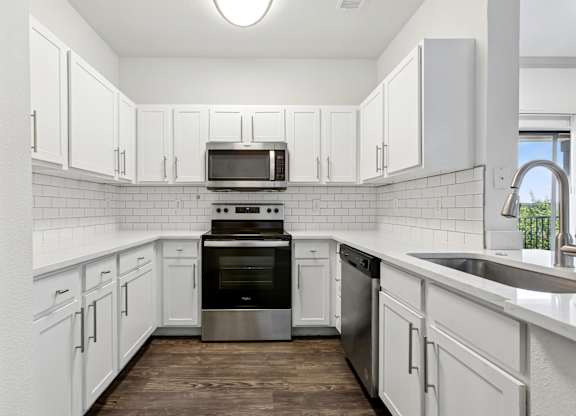 A kitchen with white cabinets and a black oven.