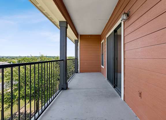 A balcony with a black railing and a view of the outdoors.