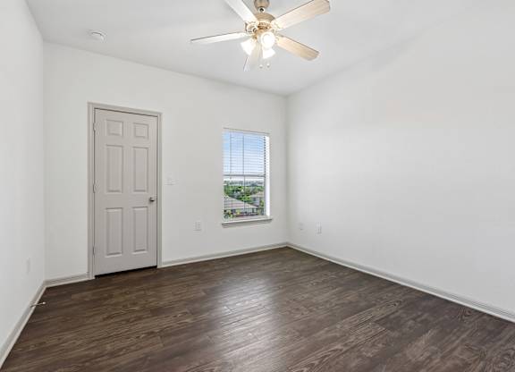 A room with a ceiling fan and a door.