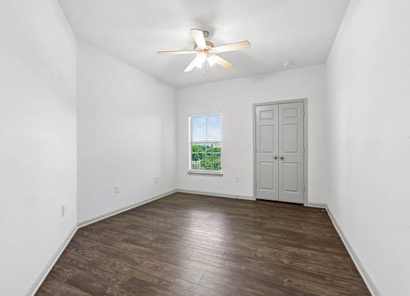 A room with a ceiling fan and a door.