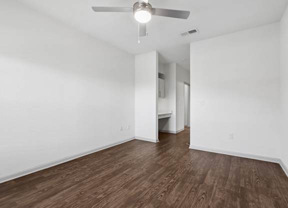 A room with a ceiling fan and wooden flooring.