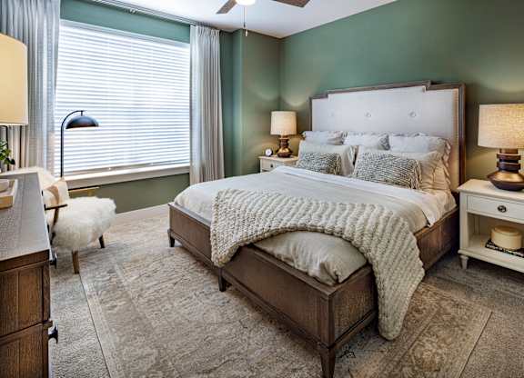 A bedroom with a large bed and a white chair at Folksong Apartments, Flowery Branch